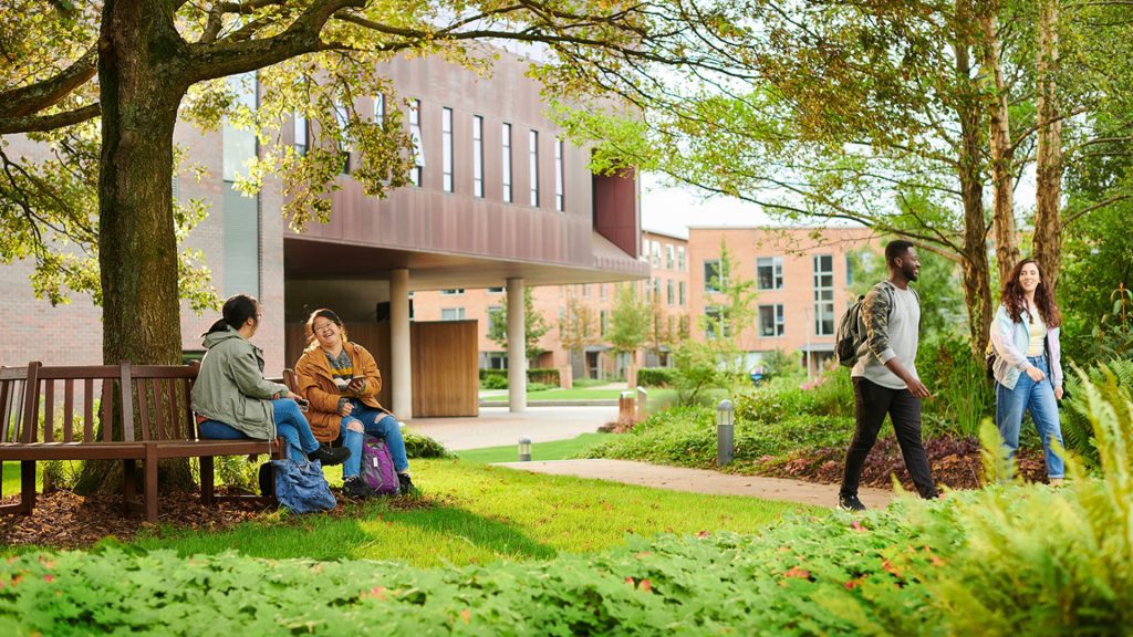 Students sitting and walking through campus by the Catalyst