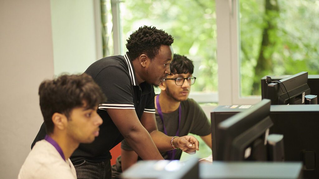 BEng Electronic Engineering students and staff sit at a computer