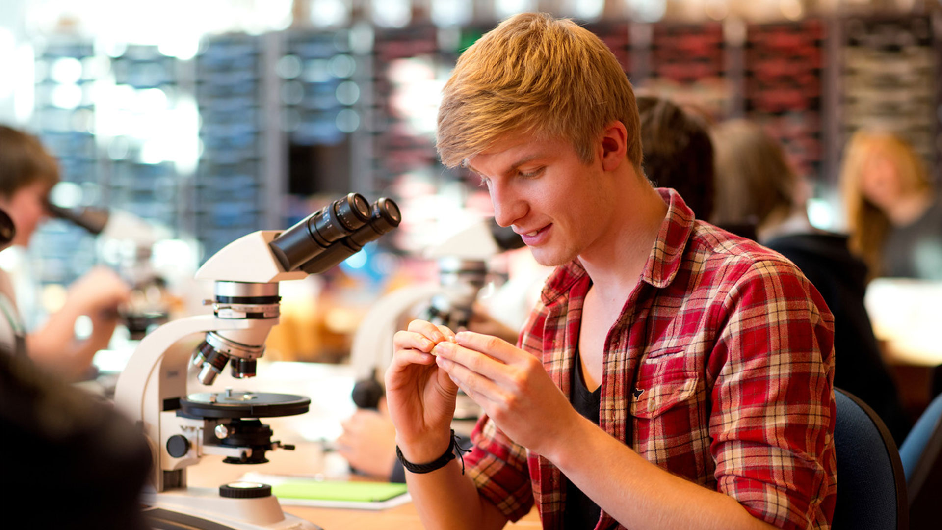A student with a microscope, studying something in his hand