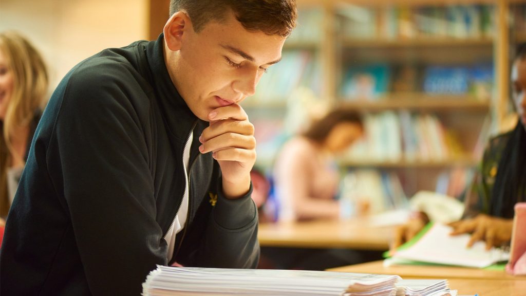 Student reading from a text book at a table