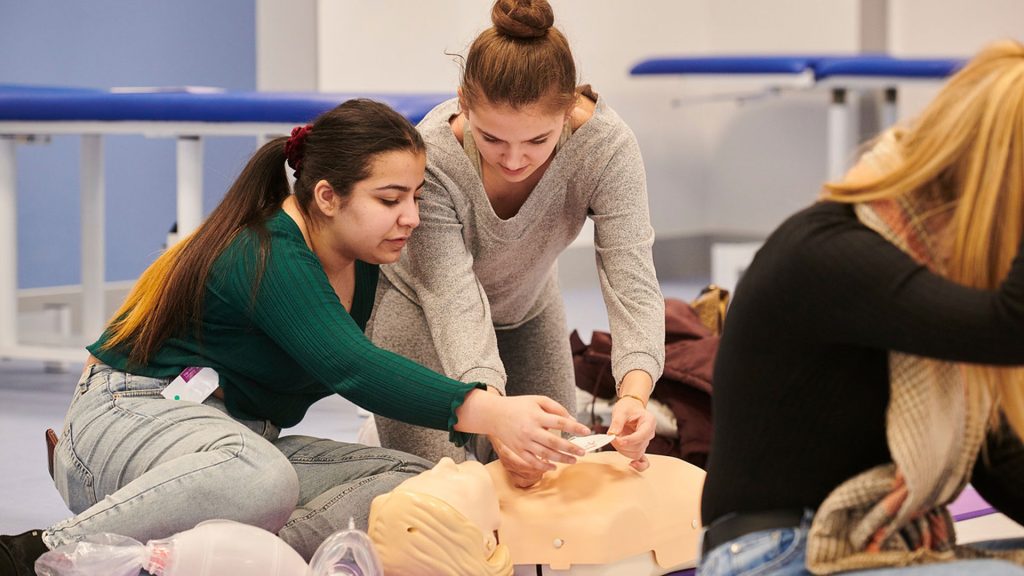 Two students at the Widening Access to Medicine event, practicing on a mannequin.