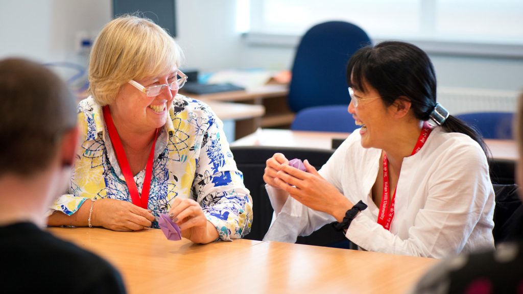 A tutor and student laugh and they make origami