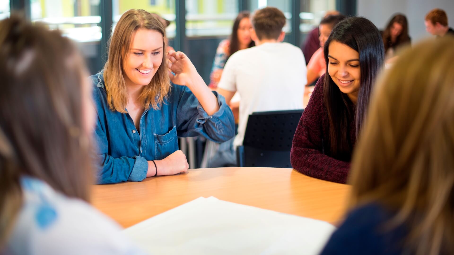 Four students sat round a table during a seminar brainstorming ideas on teamwork.
