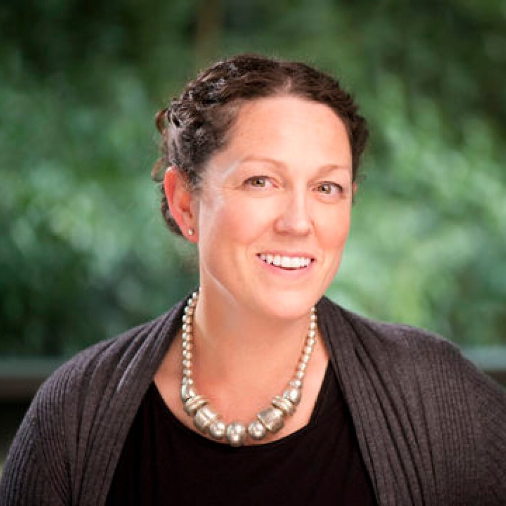 An image of the Postgraduate Research Student Tutor, Professor Lucy Bray. There is greenery in the background of the image.