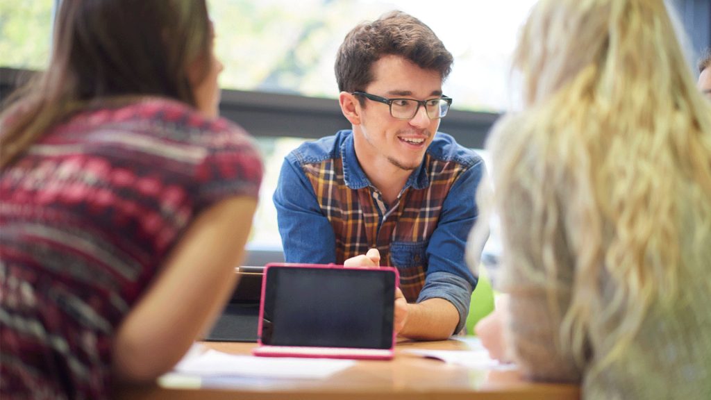 Three students sit around a table talking