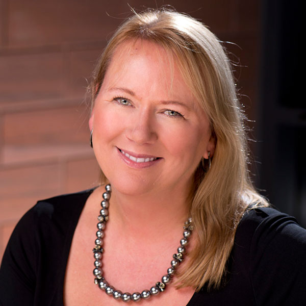 Portrait of Lorraine wearing black top and silver black necklace, smilling at camera.