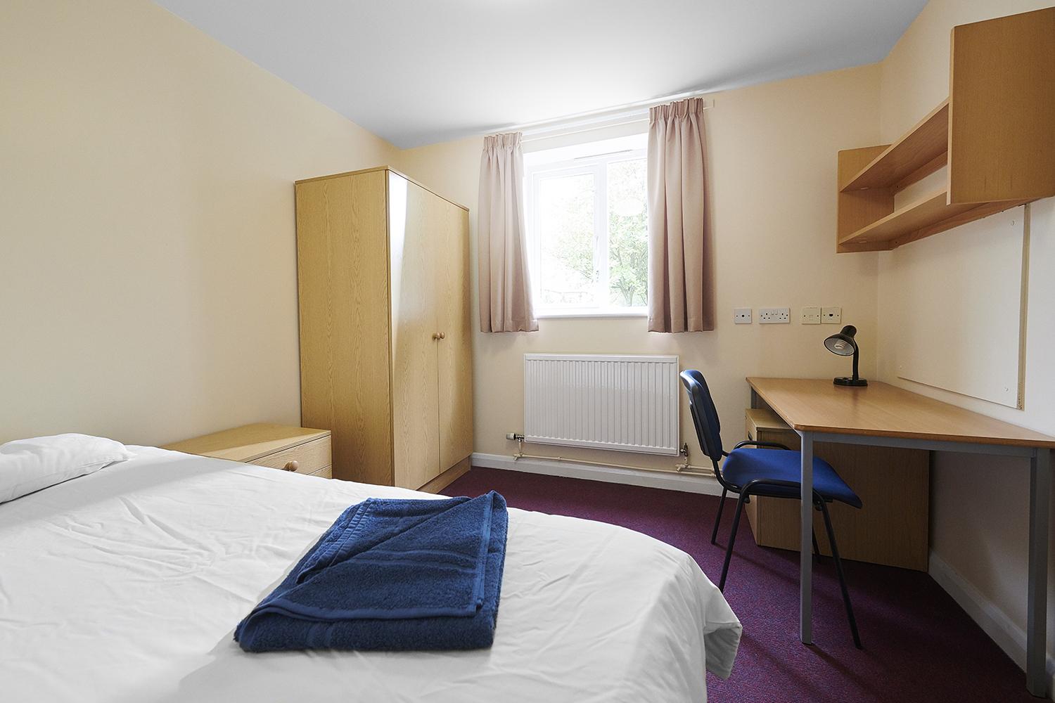 An empty bedroom in Forest Court furnished with a desk, wardrobe, bed, shelving and storage.