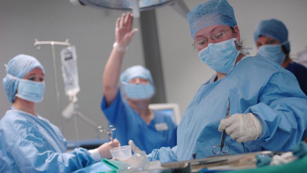 Four health workers performing surgery in an operating theatre