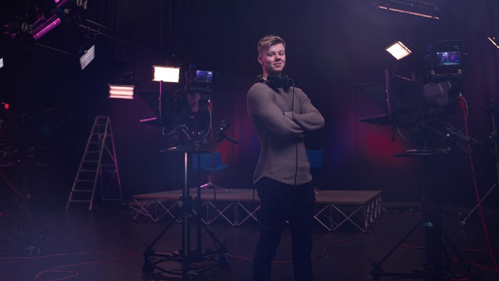 An image of a film student stood next to a camera.
