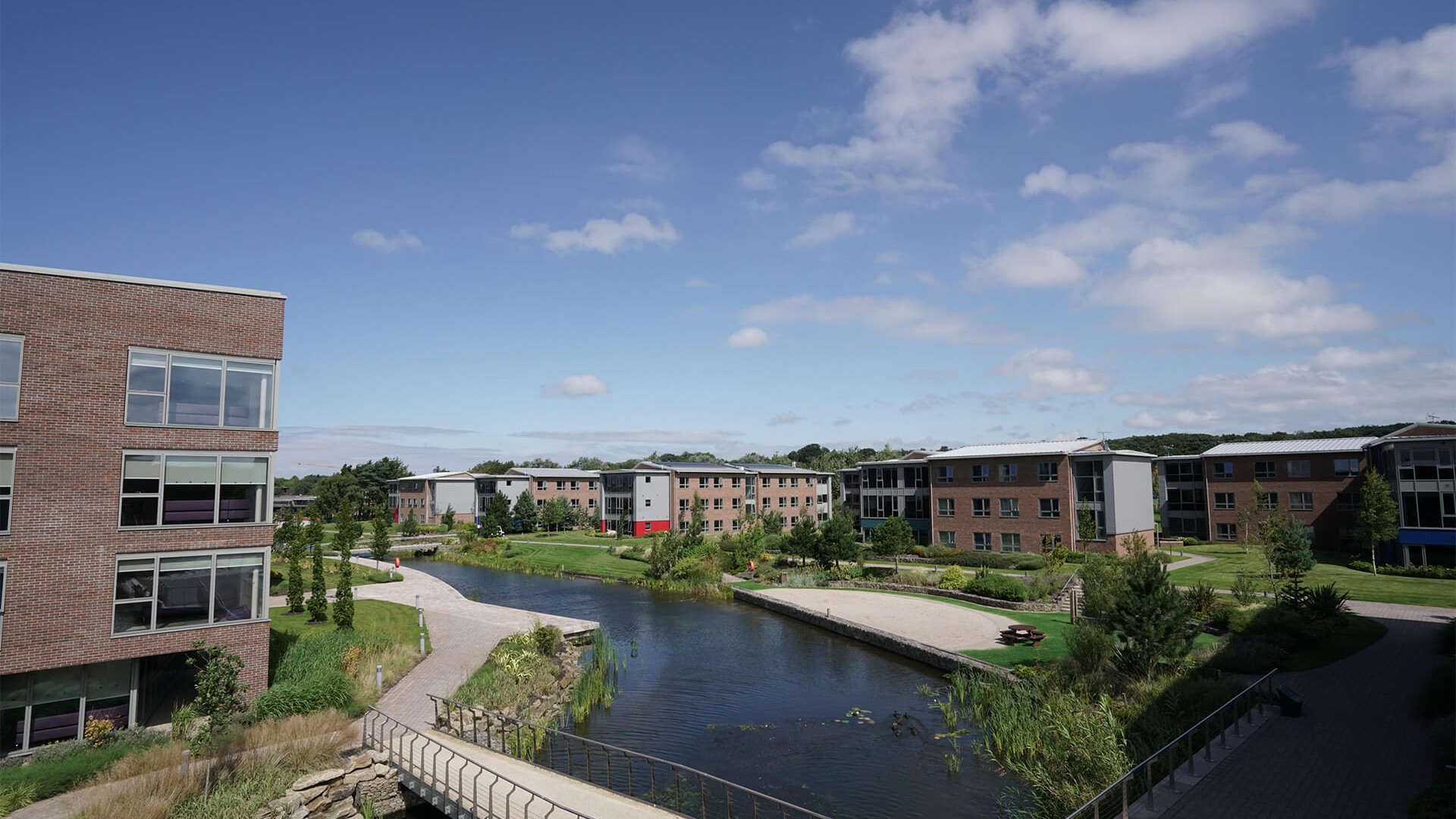 An aerial shot of part of the Edge Hill University campus, overlooking one of the lakes running through the campus and a section of the accomodation buildings. 