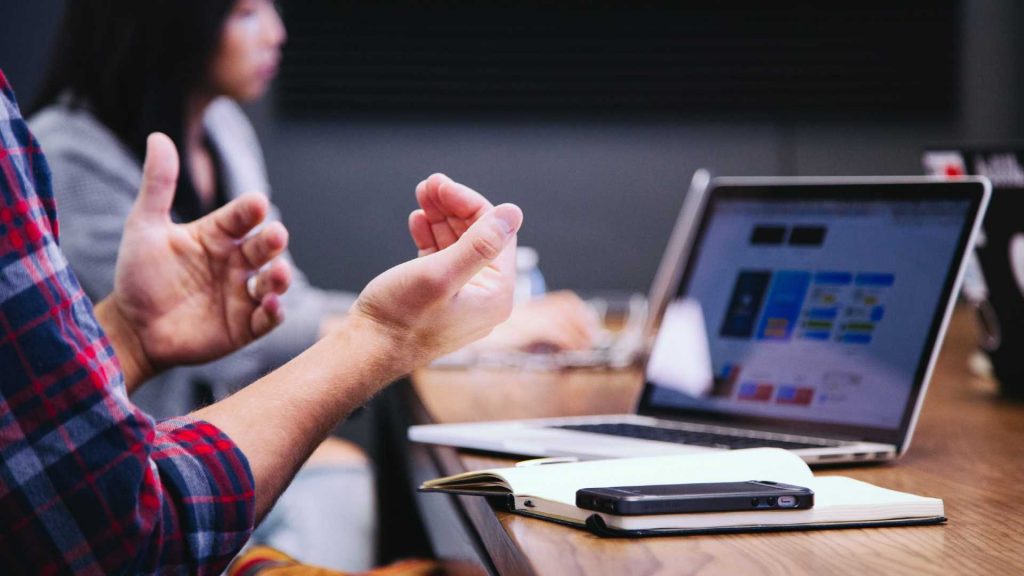 Hands, phone and laptop. Someone is taking part in an online conference.