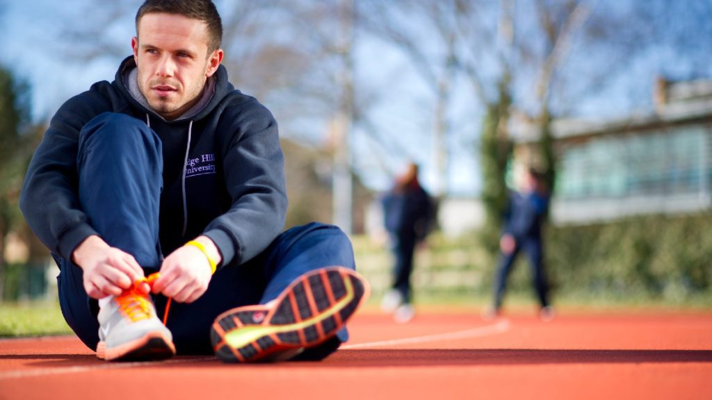 An image of a runner sat on a running track.