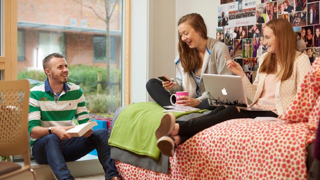 Three people are talking inside one of the accomodation rooms on the Edge Hill campus.