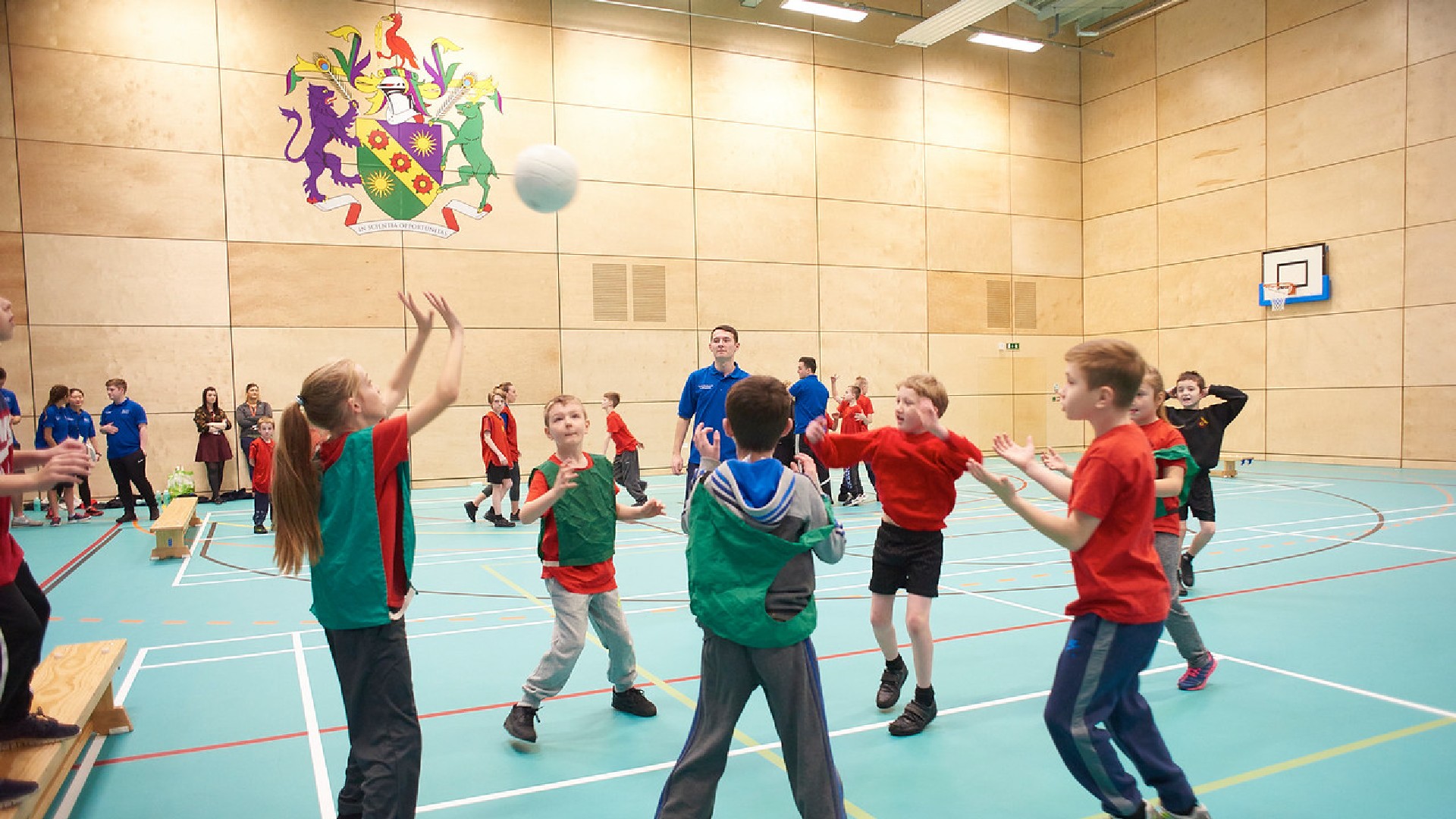 A group of children are jumping around throwing a ball into the air. 