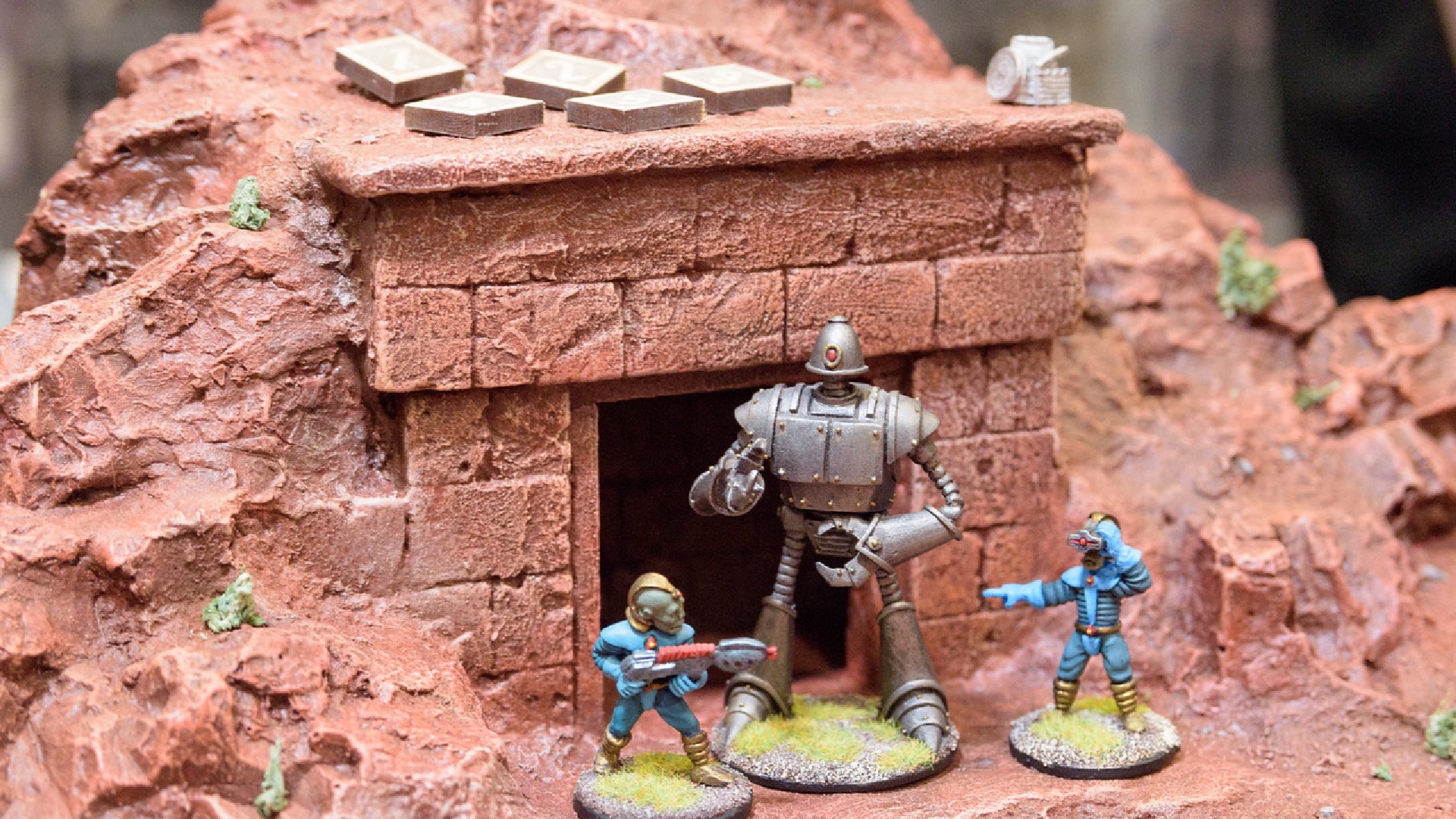 An image of three figures in front of a small building.