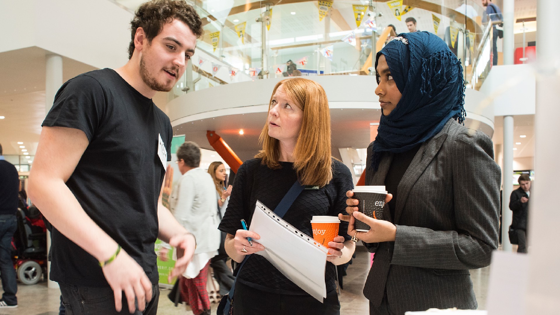 A group of students talk outside a display stall