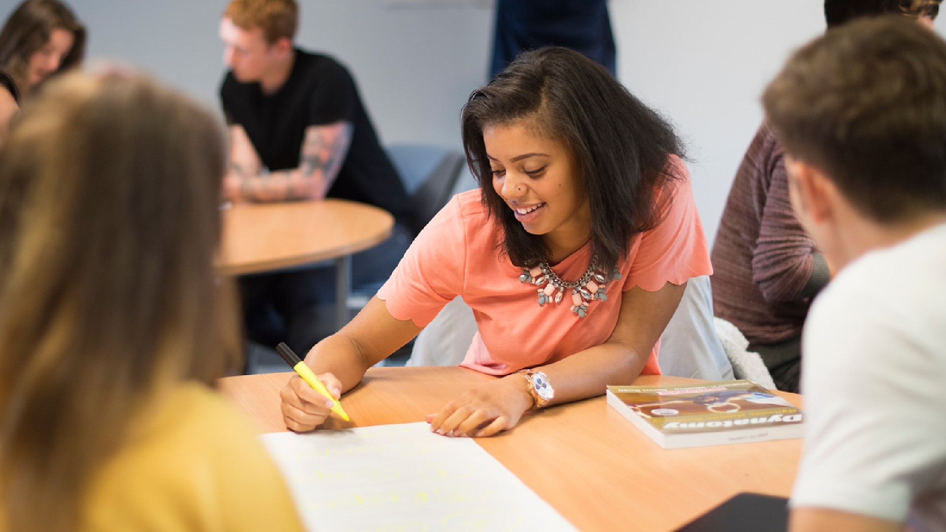 A group of student sit around a table making notes on a large piece of paper