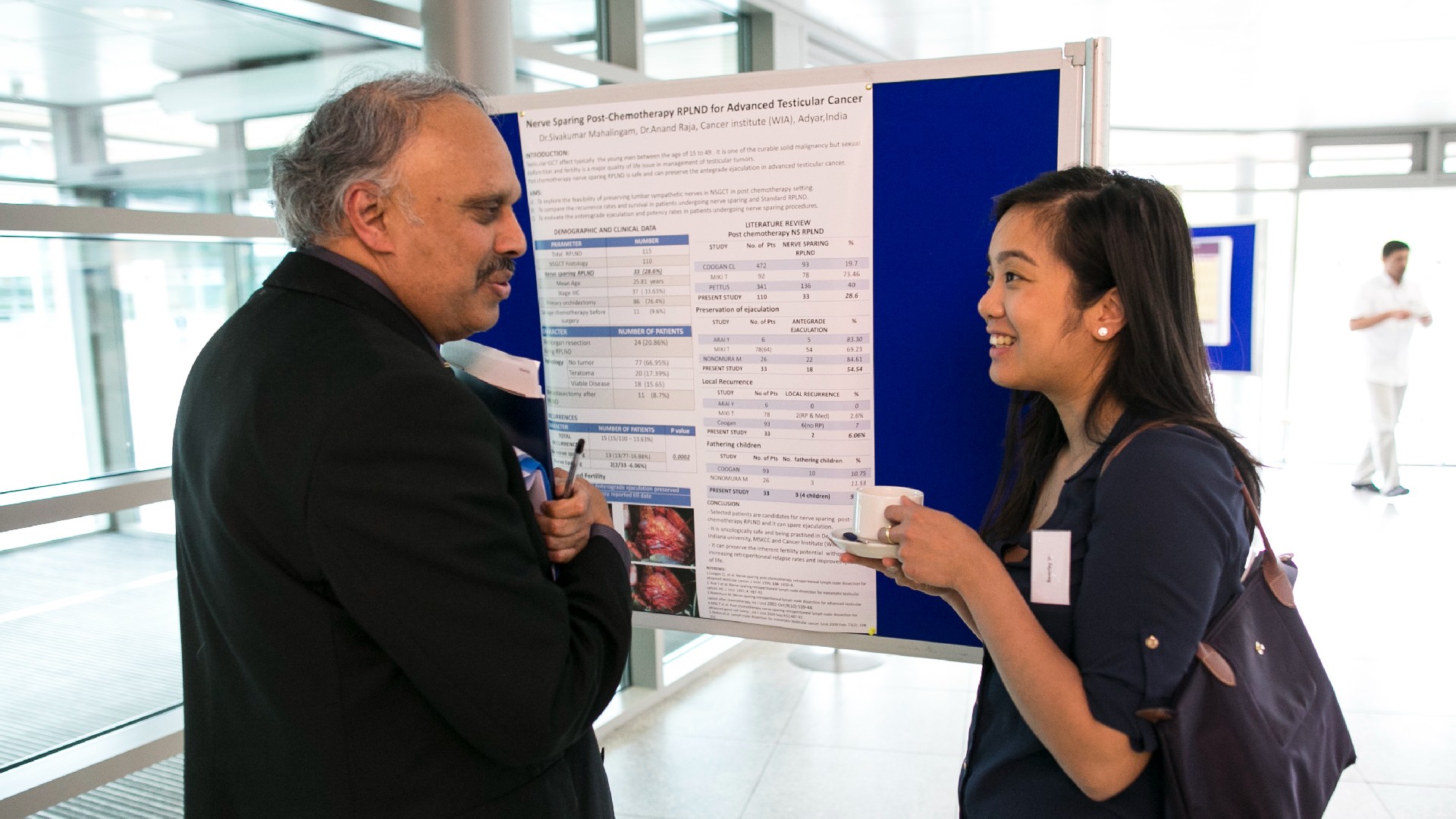 Student and pupil talking at a health conference whilst having a cup of tea
