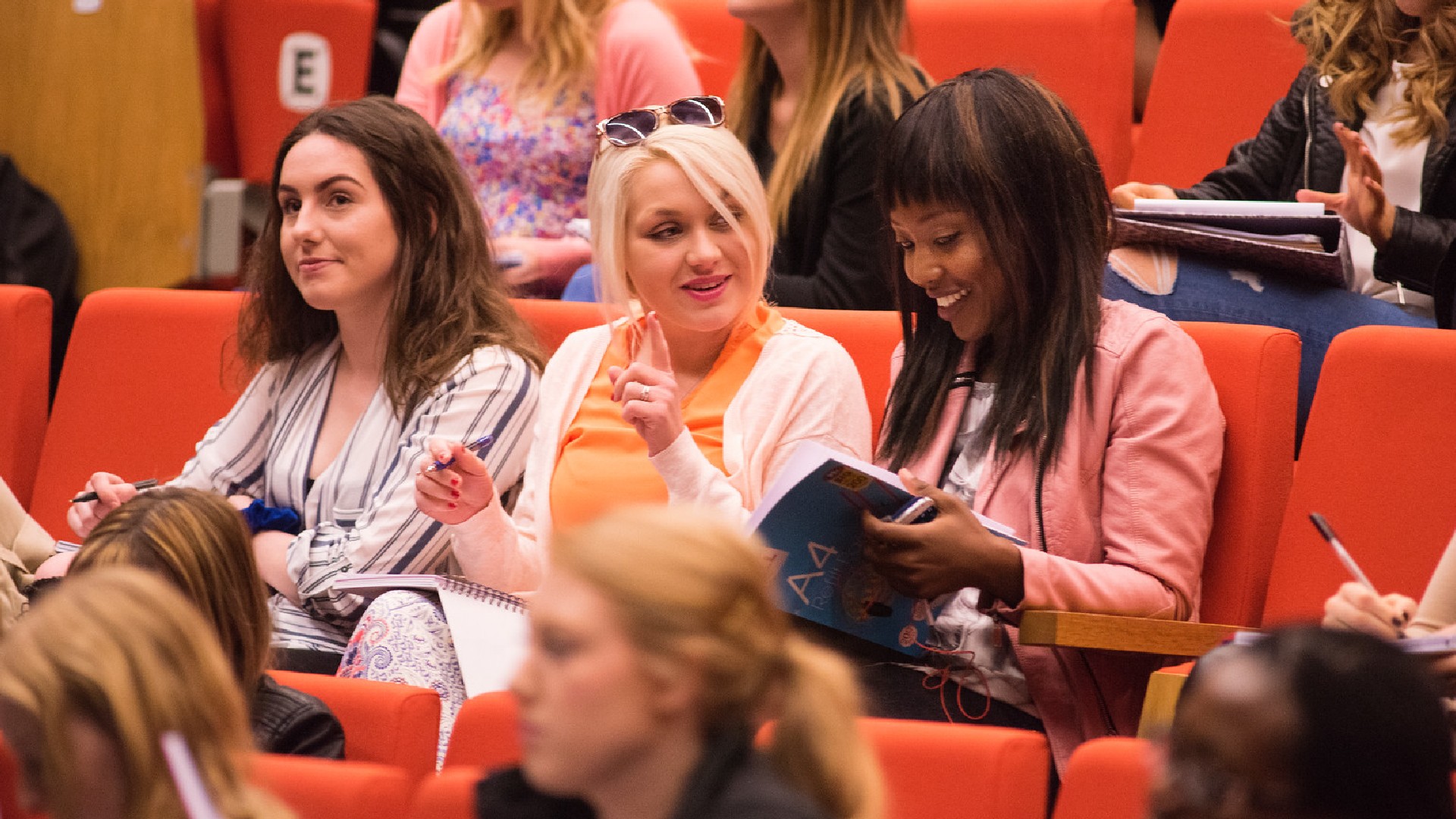 A row of nurse students sat in a lecture theatre smiling at eachother