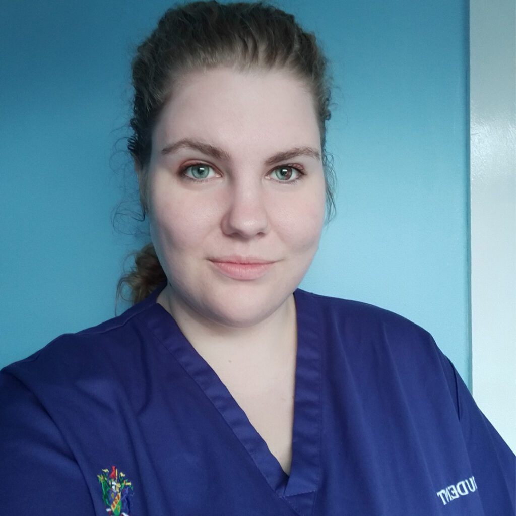 Sophie Sutton wears blue student scrubs and smiles at the camera.