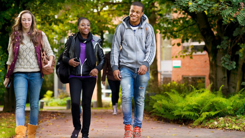 Three students walk along a path on the Edge Hill University campus