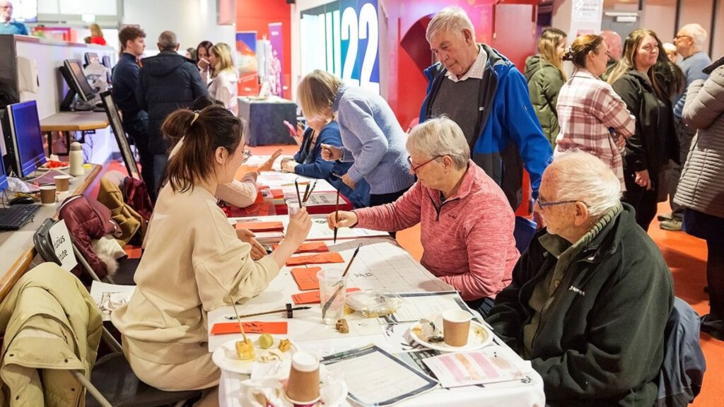 Visitors to the Healthy Brain showcase sit around a table and take part in Chinese paper cutting.