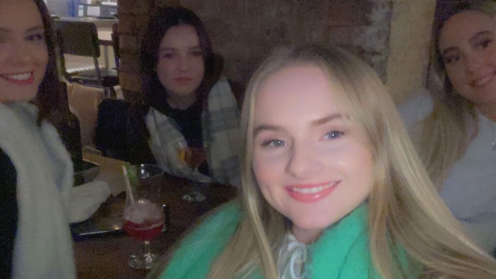 Freya and friends smile to camera while they have drinks