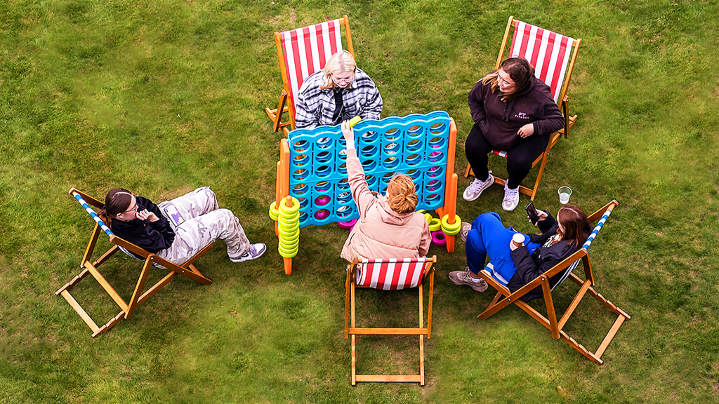 Students sitting in striped deckchairs play Giant Connect 4 on Welcome Sunday.