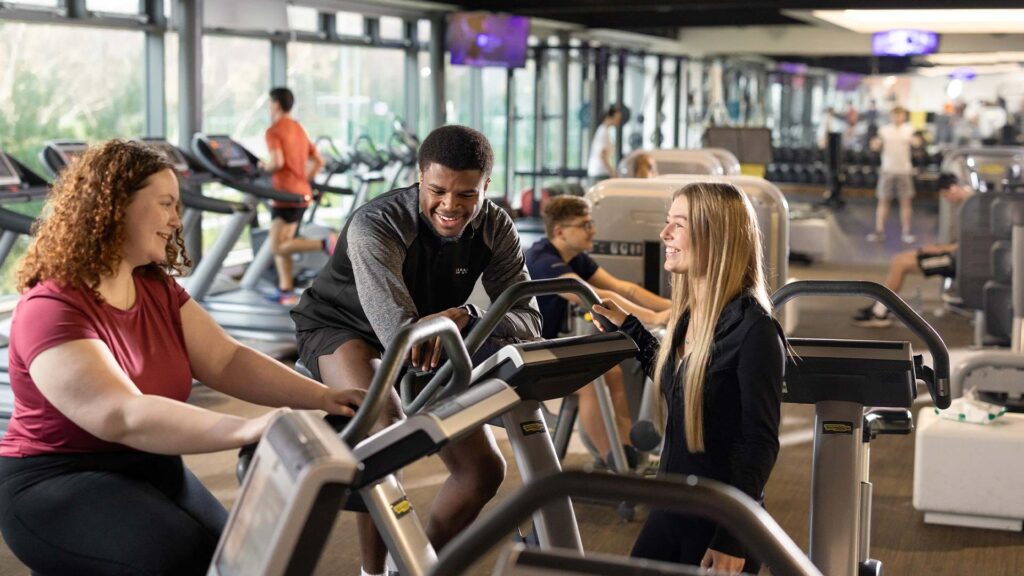 students sat on gym equipment while talking in the sports centre