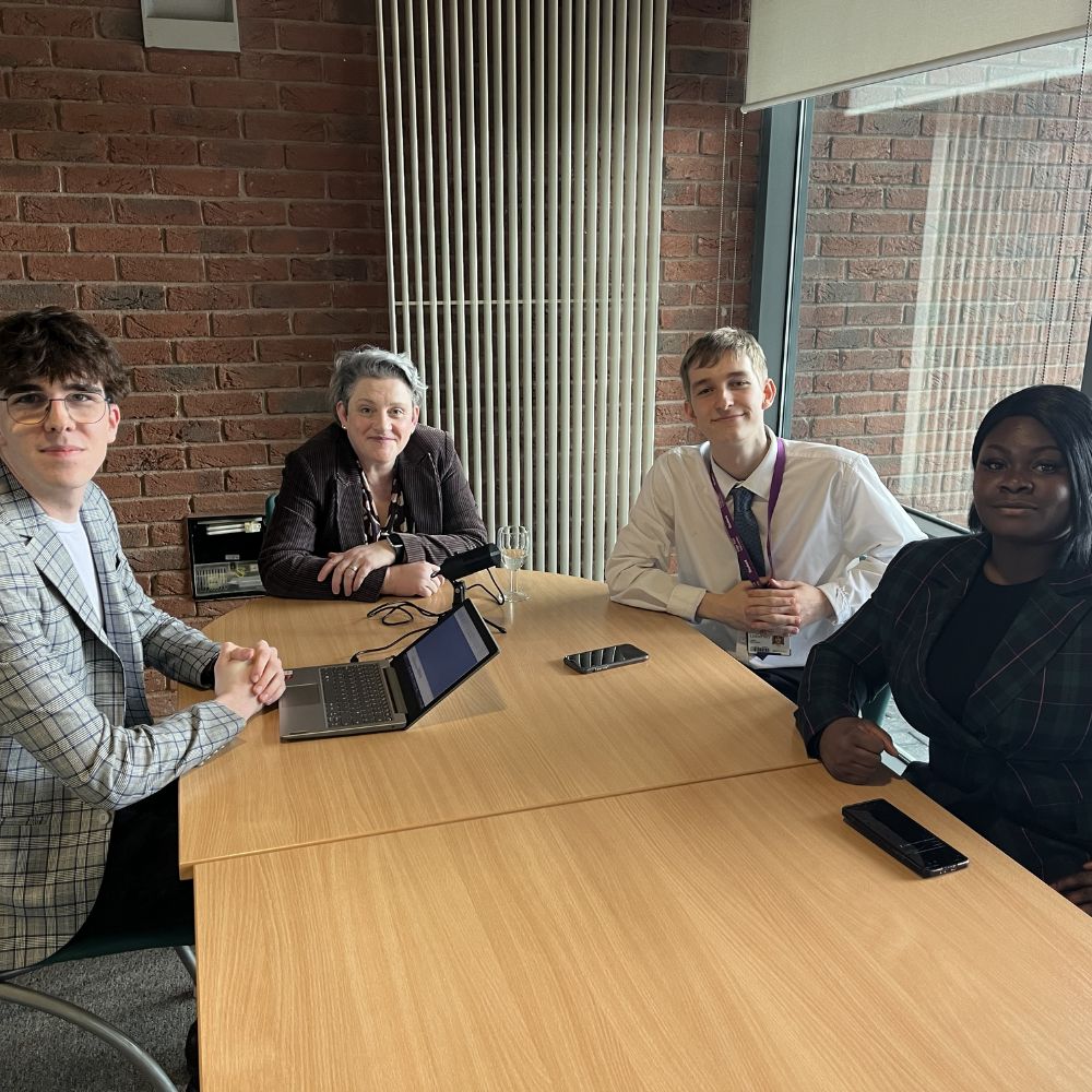 3 students sat around table interviewing ashley dalton