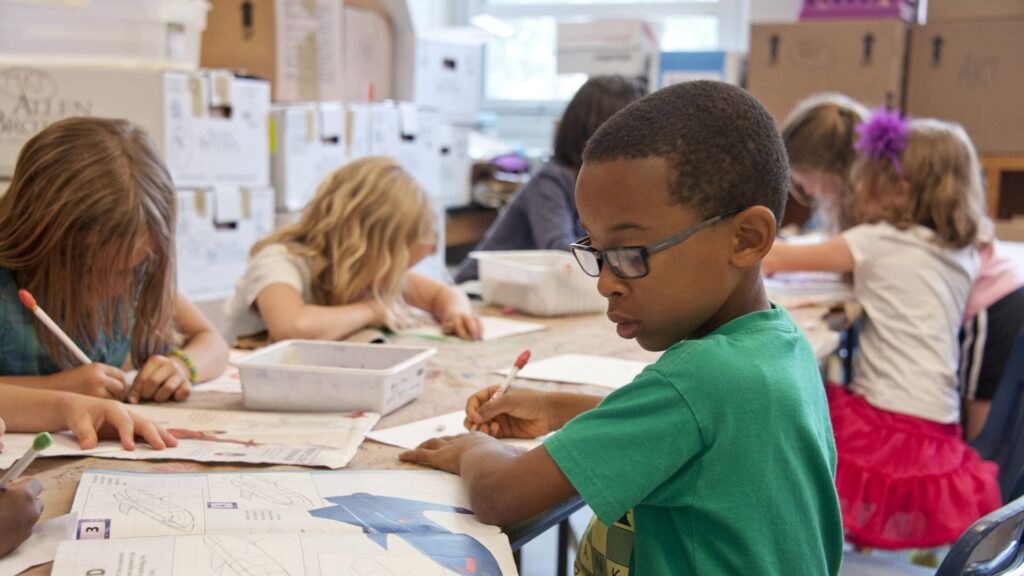 Primary school children sat around a table working through workbooks