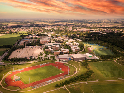 An aerial view of the Eastern Campus at sunset. The running track and grass pitches are visible.