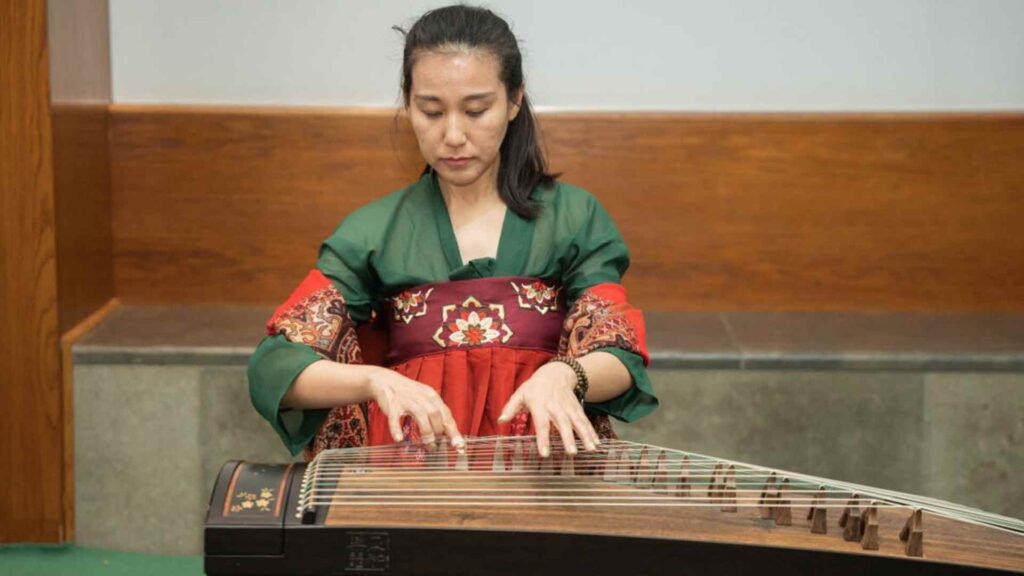 Performer playing a harp at the Chinese New Year event in the hub, wearing green and red dress.