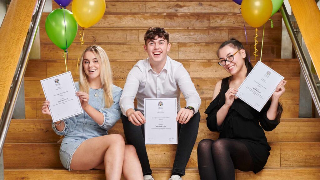 Students with their scholarship awards sitting on steps in the Hub.