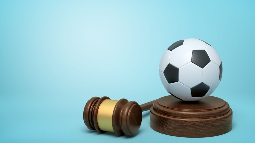a football placed on top of a block with a gavel next to it, all on a blue background.