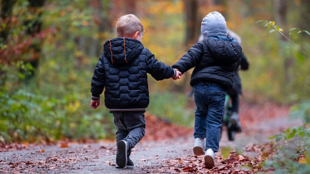 Two children skipping and playing outside in a park