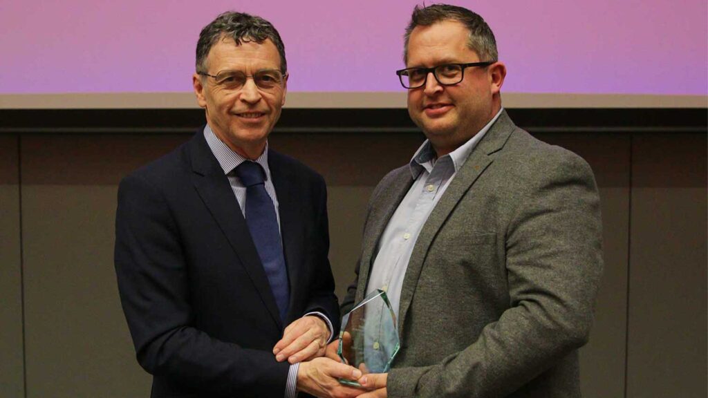 Professor Andy Smith with a glass award stood next to Mark Allanson