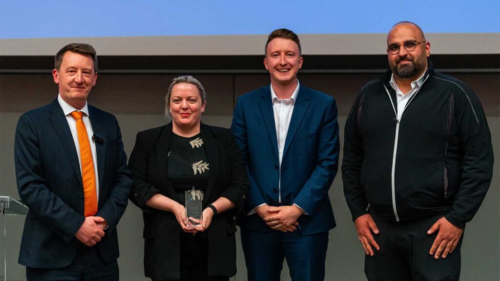 Three colleagues of the British School of Kuwait and their glass award stood next to Liam Owens