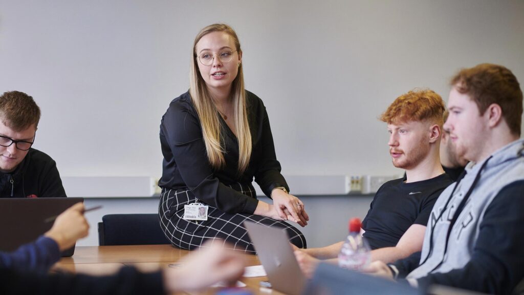 Students engaging in discussion with tutor in a seminar in Business School.