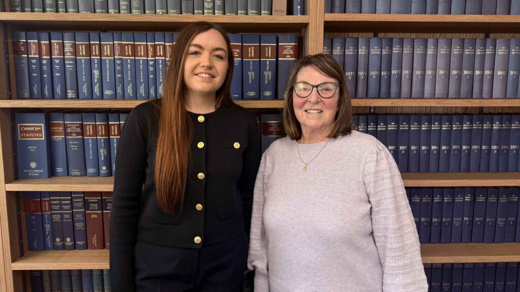 Wigan FC MD Sarah Guilfoyle and Non-Executive Chair Brenda Spencer, stand in front of law books at Edge Hill University.