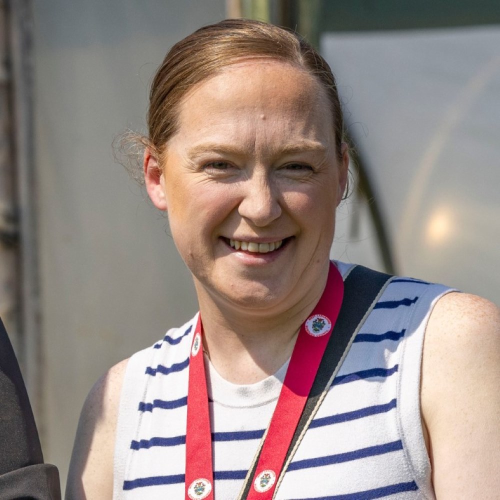 Photo of Cllr Melissa Parlour, wearing a stripy white and blue vest, smiling.
