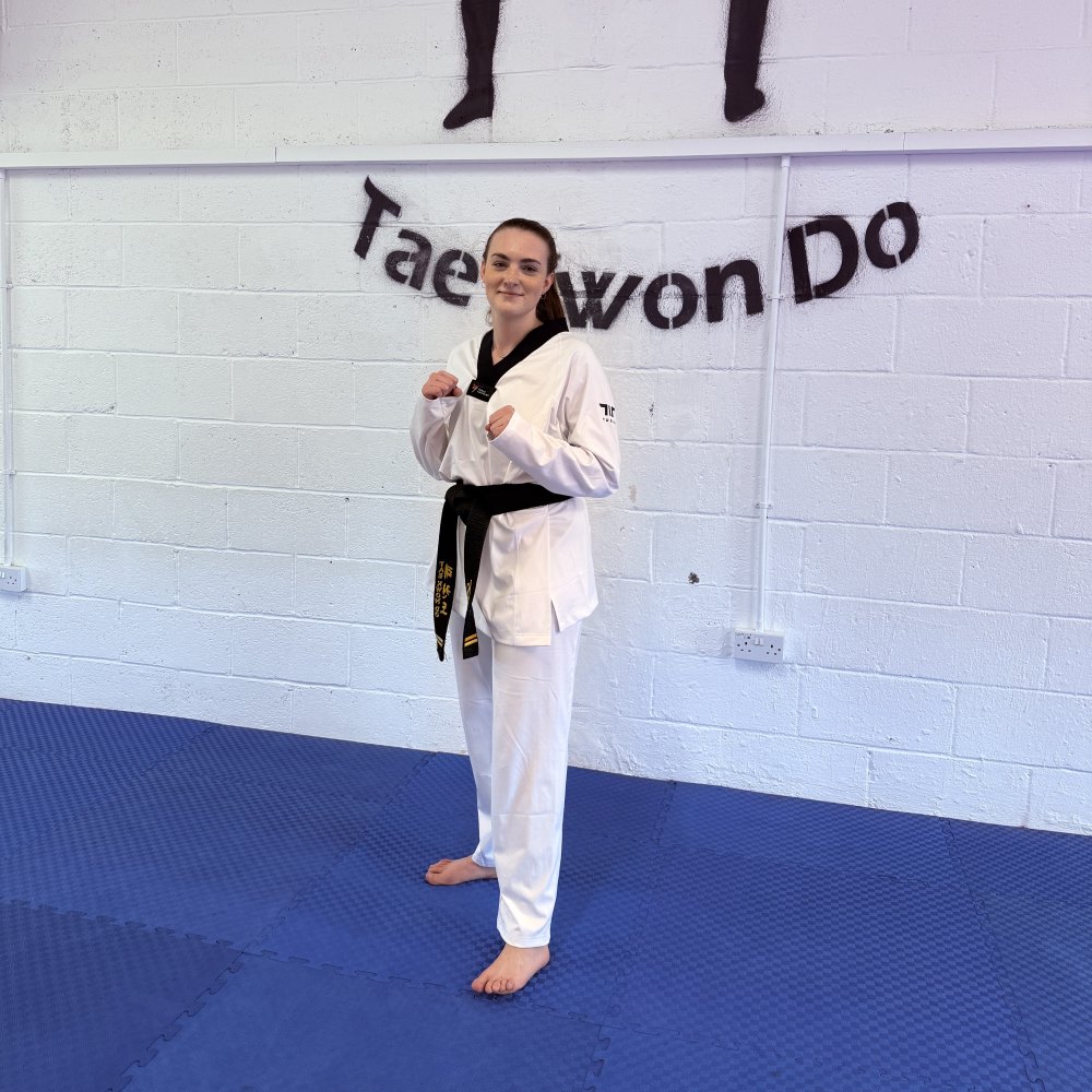 Taekwondo student standing in front of white wall at Taekwondo gym in battle stance.