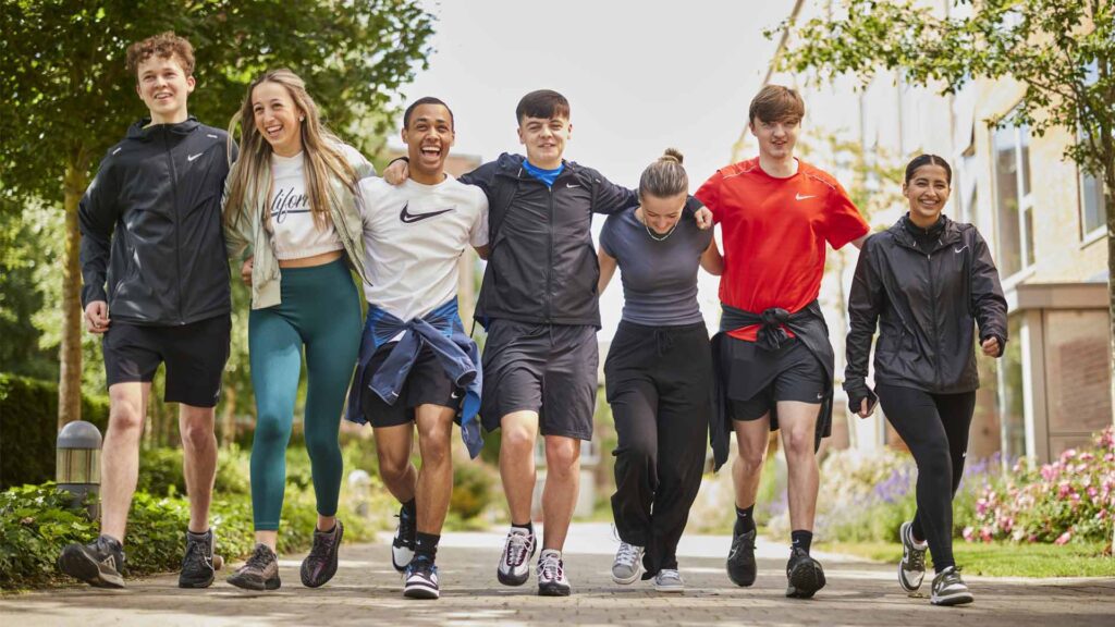 group of students walking round campus while smiling and laughing