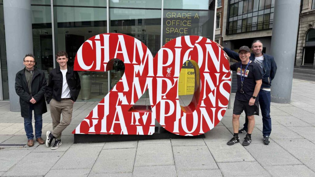 Student Darol with 3 of his LFC design team outside a big sculpture of the number 20 with LFC all over it.