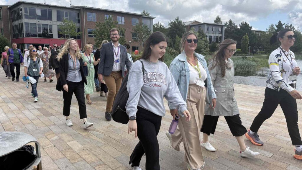 staff and guests walking near the Edge Hill lake on a sunny day.