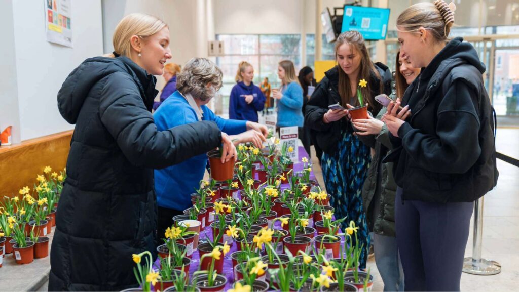 Students stood on one side of the table being passed plants by staff on the other side