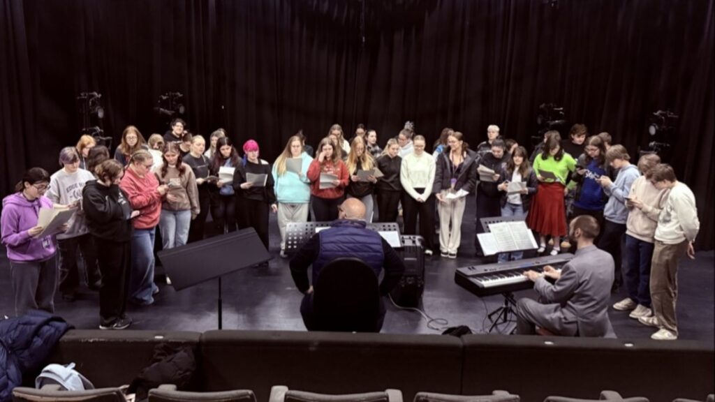 image of50 plus students standing in a semi circle while singing.