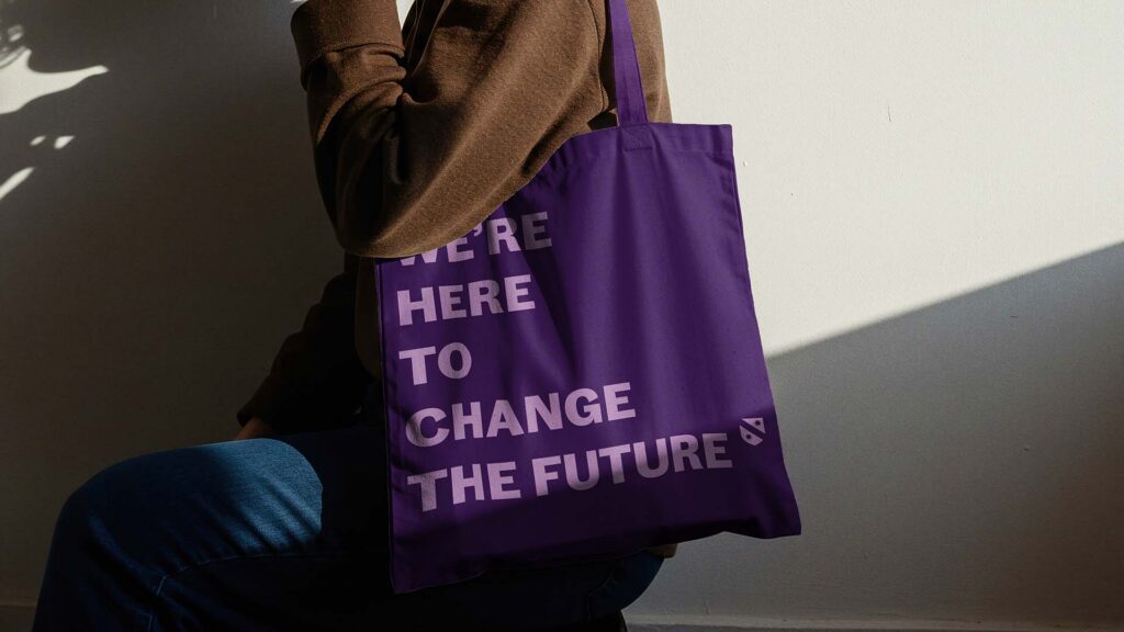 A mock up of a purple tote bag, with the words, "We're here to change the future" on the side.