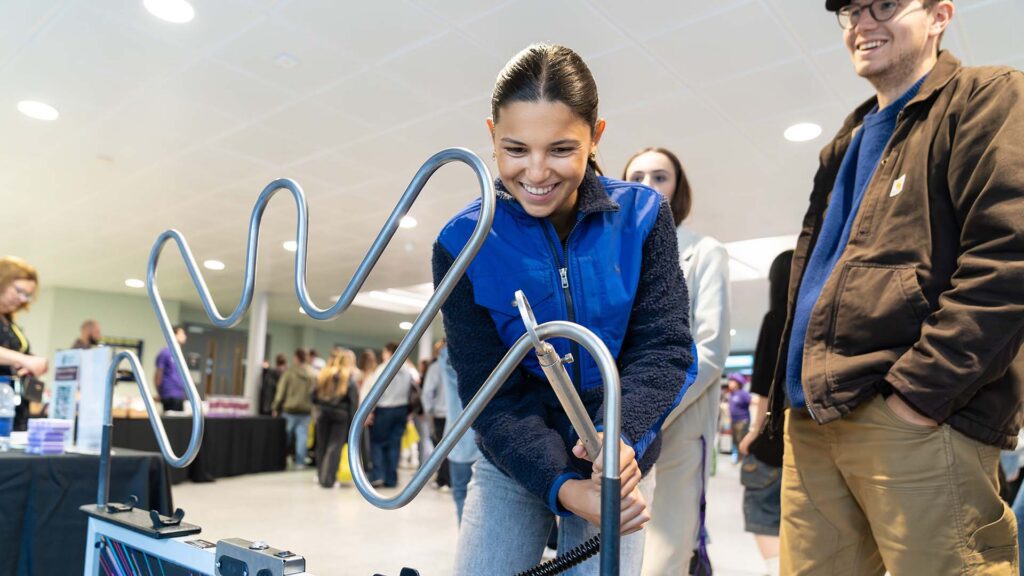 An open event, with a prospective student playing with a buzz wire game.