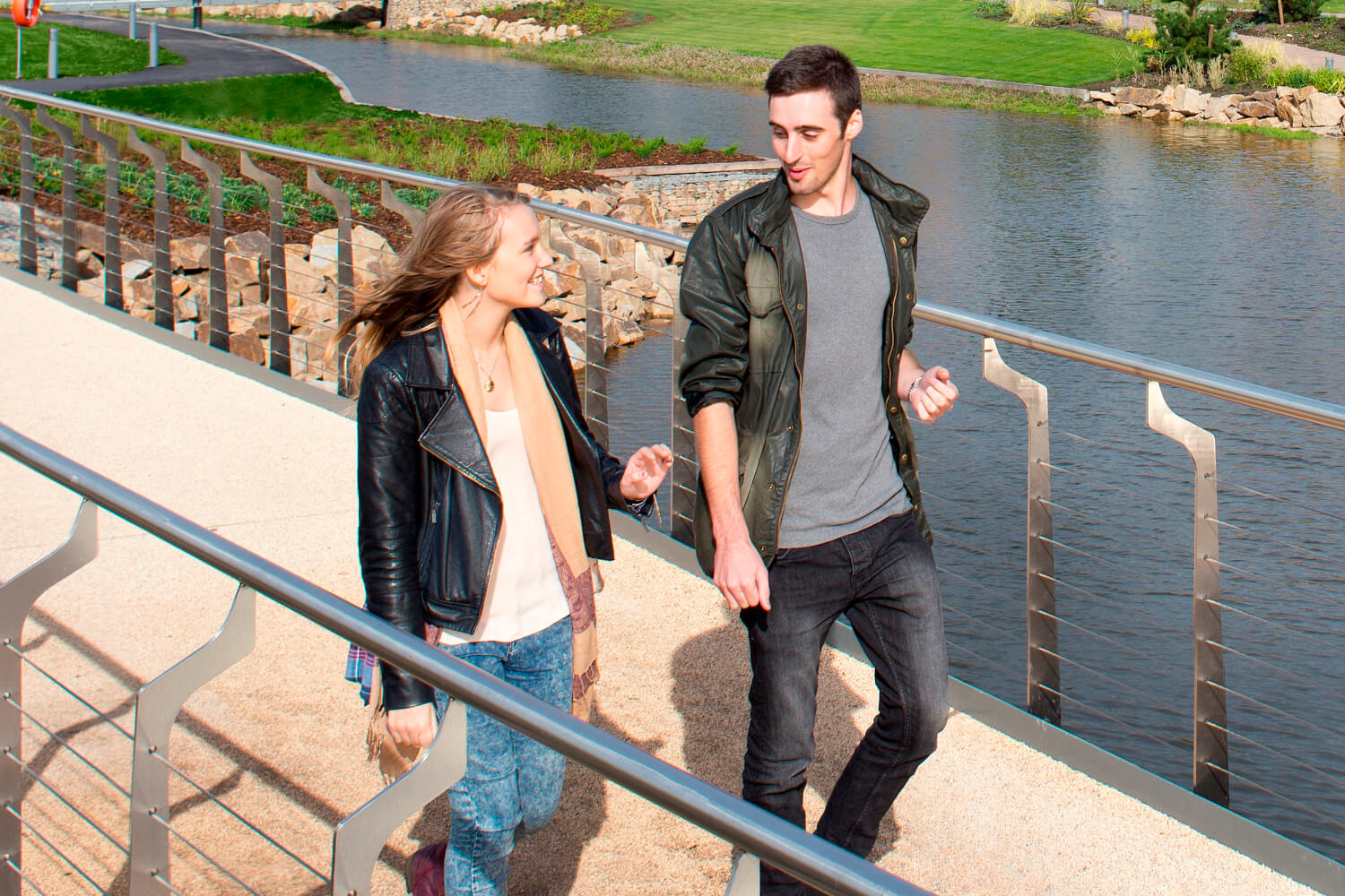 Campus and facilities - Two students walk across a bridge over a lake on the eastern side of the campus.